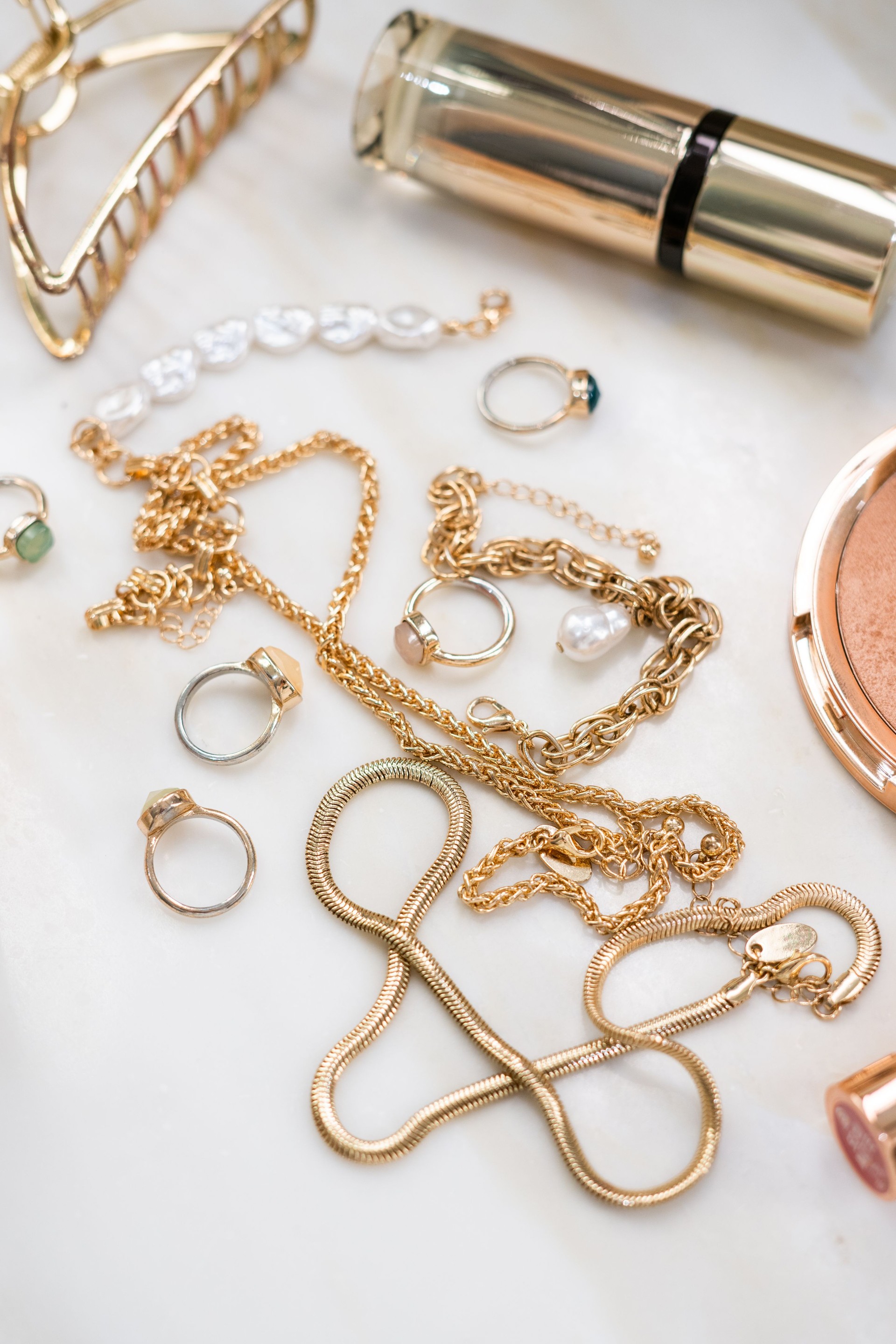 Gold jewellery and make up products  on a marble surface